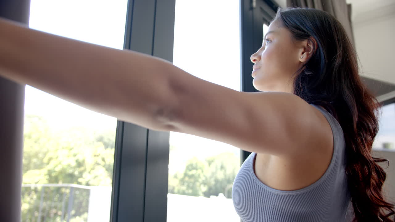 행복한 이중 인종 십대 소녀는 커튼을 끌고, 은 창문 밖을 바라보고, 복사 공간, 느린 동작