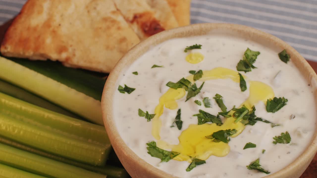 Greek Tzatziki sauce of salted strained yogurt or diluted yogurt mixed with cucumbers and mint, garlic, salt, olive oil on top. High quality 4k footage