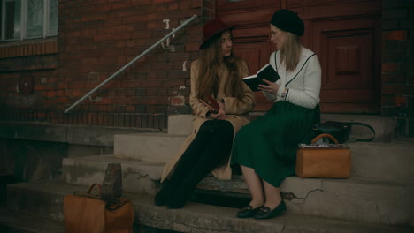 two women reading book at stairs