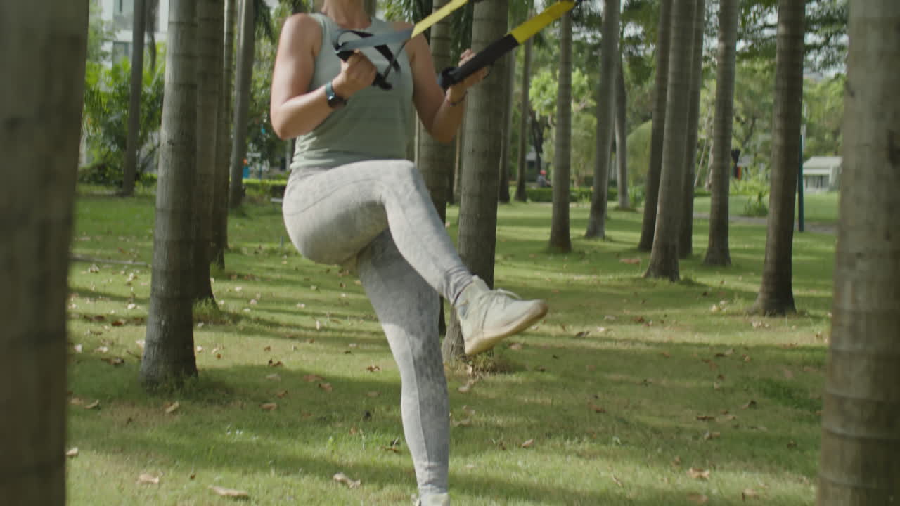 Woman Practicing Suspension Training in Park