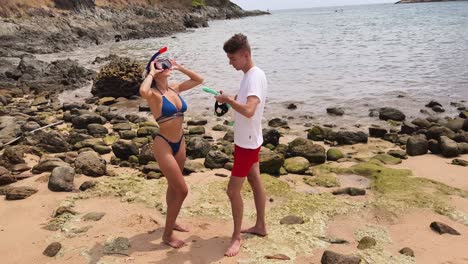 couple preparing for snorkeling adventure at beach