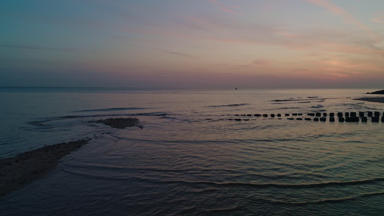 scenery of the sunset on the seashore of North Sea Atlantic Ocean beach with calm waves and beautiful skyline horizon with evening afterglow. Netherlands, Europe
