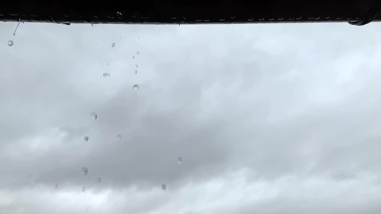 Looking up at leaking dripping gutter droplets on overcast rainy weather day