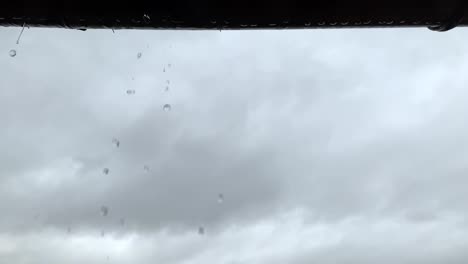 looking up at leaking dripping gutter droplets on overcast rainy weather day