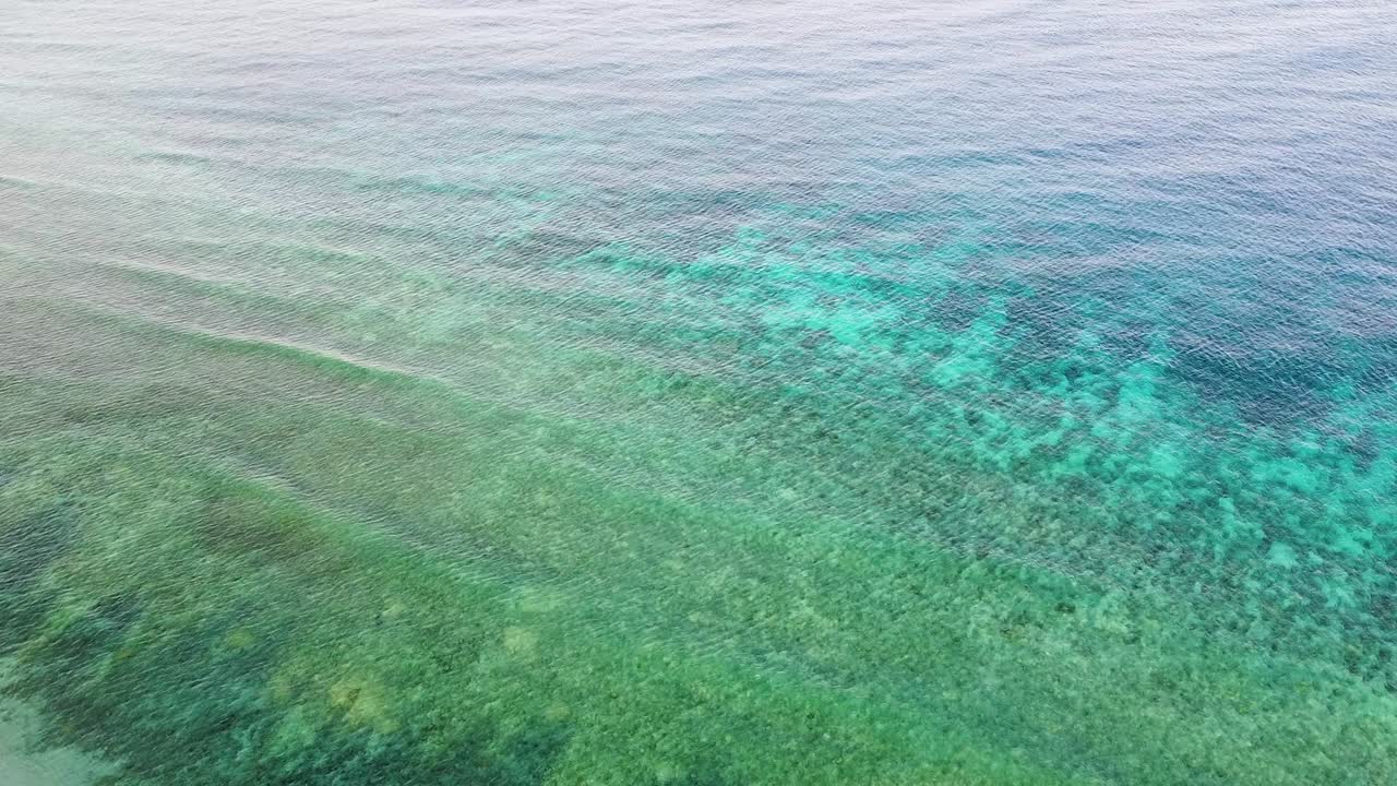 Static aerial drone view of turquoise ocean water, waves, and coral reef, in Coral Triangle region of Timor-Leste, Southeast Asia