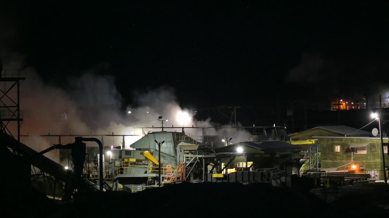 산업 연기 속에서 제재소 내부 작업의 야간 모습