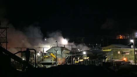 a nighttime look at the inner workings of a sawmill amidst industrial smoke