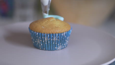 slow motion of isolated cup cake, decorating with blue sugar icing