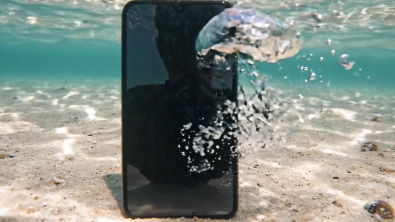 An underwater exploration reveals a smartphone submerged in clear blue water, capturing unique reflections and bubbles around it, highlighting the contrast between technology and nature.