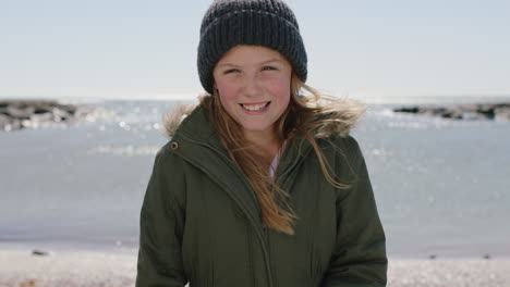 portrait of happy girl on beach smiling cheerful dressed warm wearing beanie hat and coat