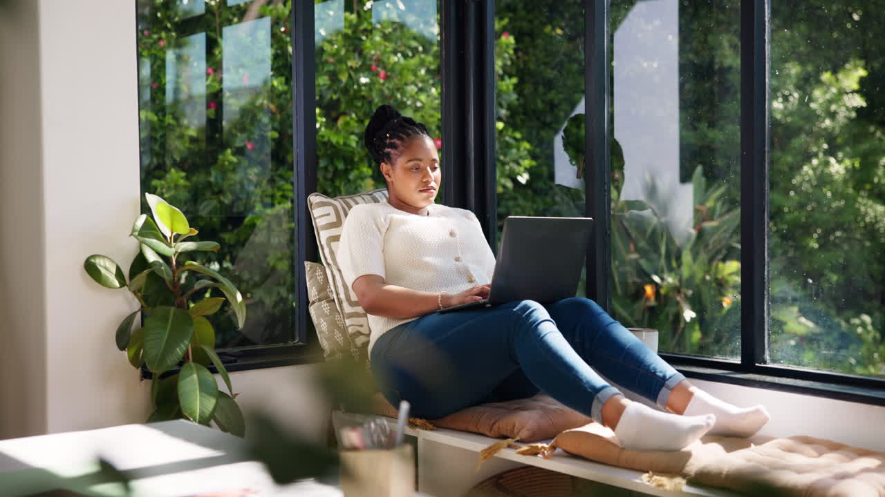 Young Woman Working on Laptop in Cozy Window Seat