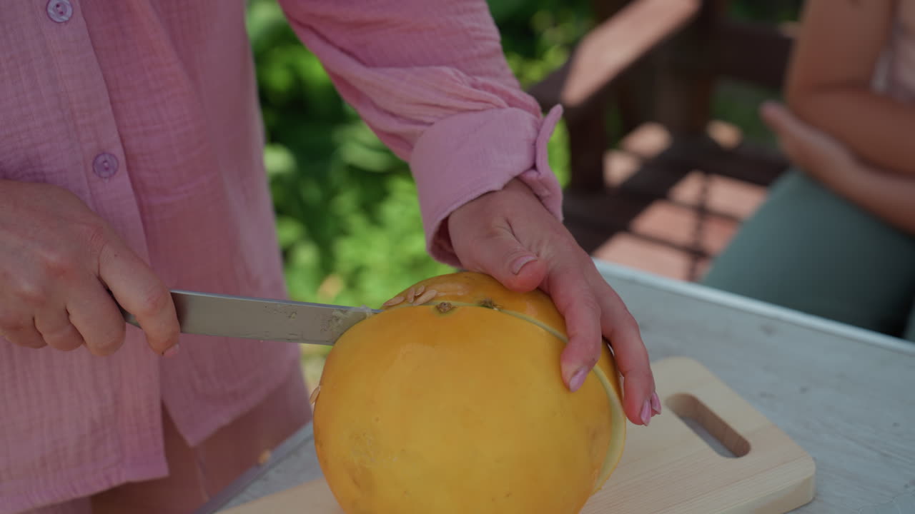 Children Observe Warm Family Activity, Loving Grandmother Prepares Melon With Children Gathered, Closeup Of Grandma And Children Sharing Tender Family Tradition Involving Melon Preparation