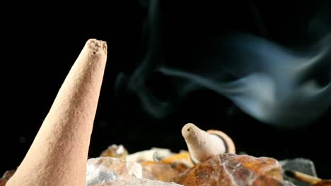 slowly pulling away from a lit incense cone, smoke billowing