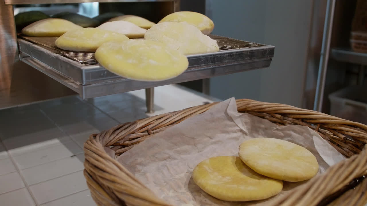 Pane pita fatto in casa che cade dalla fine del nastro trasportatore dopo la cottura, in un cestino pronto per essere servito ai commensali.