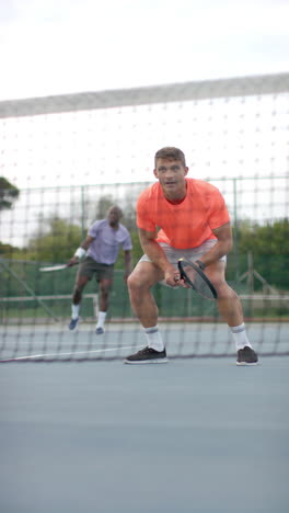 vertical video of diverse male tennis players playing tennis in slow motion