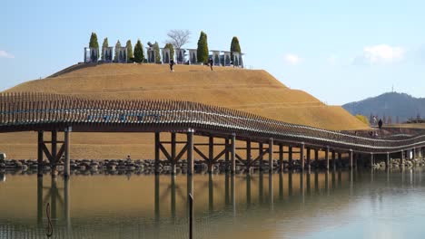 Suncheonman-Bay-National-Garden---People-walking-on-Bridge-of-Dreams-over-the-lake-and-Bonghwa-Hill-Autumn-Park-skyline,-Suncheon-city,-South-Korea