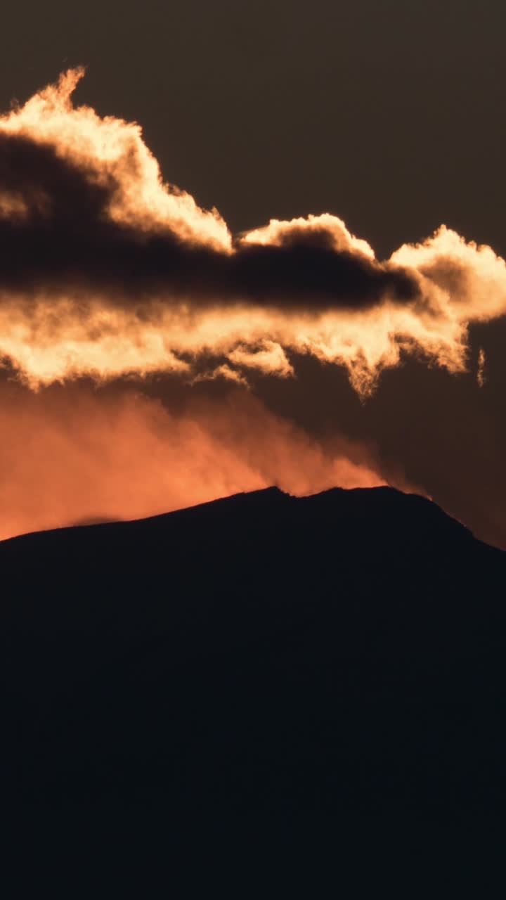 Zeitraffer eines goldenen Sonnenuntergangs hinter einer Bergsilhouette