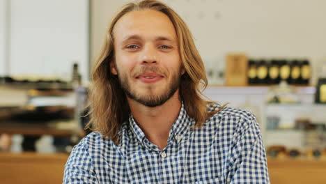 close-up view of caucasian blond man with long hair smiling at camera sitting at a table in a cafe