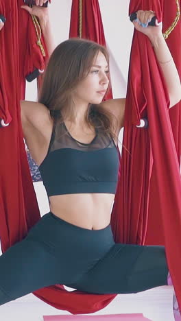 ladies group practices oriental fly yoga warrior position holding hammocks and looking at window close view slow motion