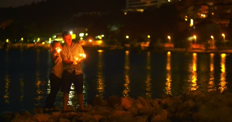 couple holding sparklers at seashore 1