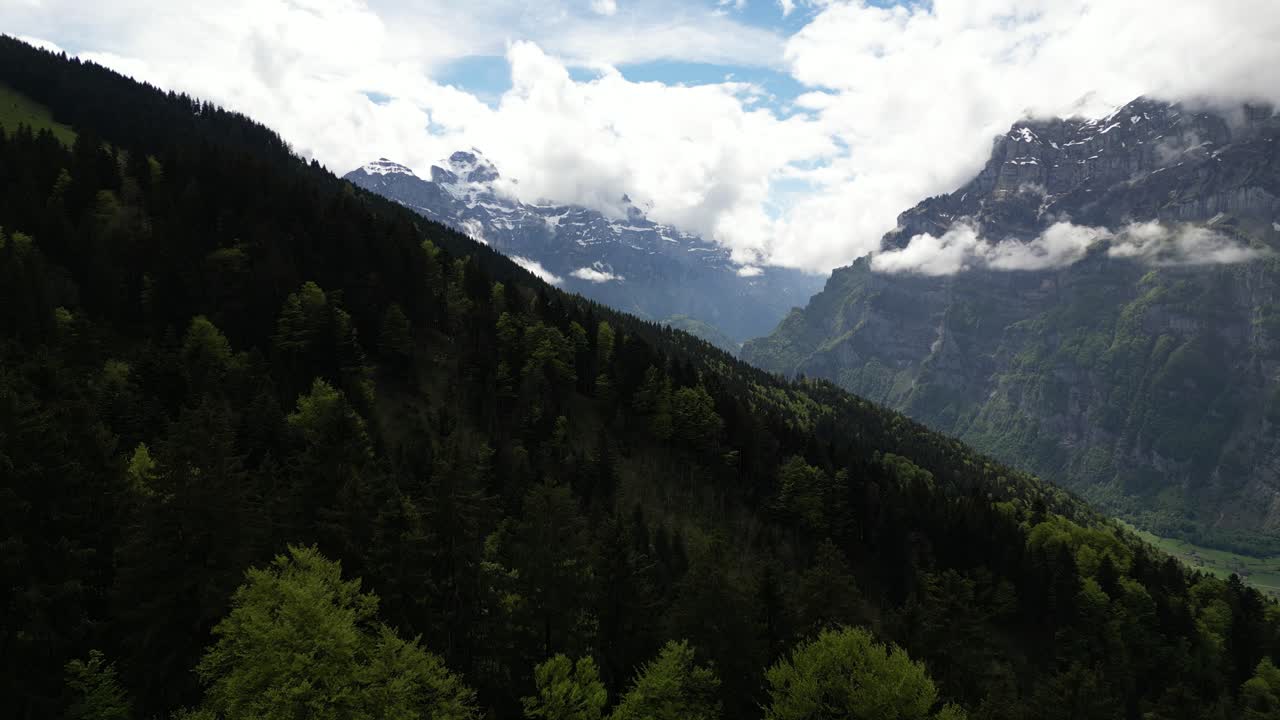 vista aérea de una cordillera con picos cubiertos de nieve en medio de las nubes en glarus, suiza, destacando la majestuosidad del desierto alpino