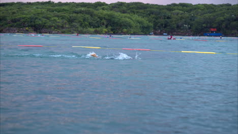 cámara lenta de atletas profesionales nadando en una competencia de triatlón en el mar