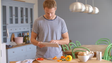 hombre sigue la receta en la tableta digital en la cocina filmado en r3d