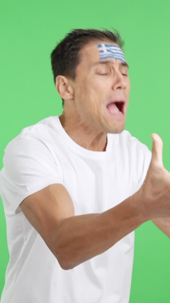 Nervous man cheering for Greece during a match looking away