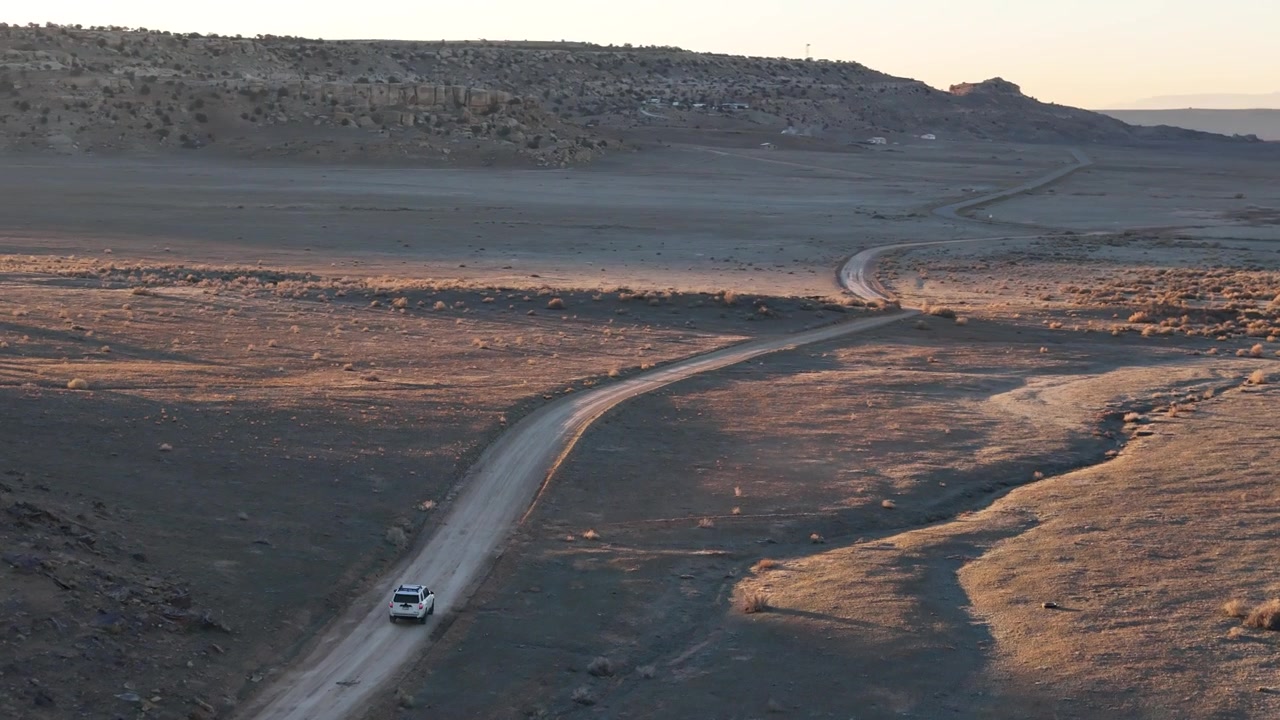 Vista aerea di un veicolo SUV bianco in movimento su una strada desertica nel Colorado sudoccidentale, USA. Ripresa con drone.