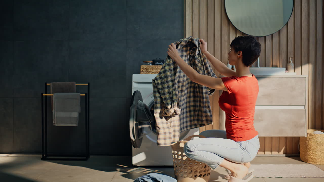 Pretty girl sorting clothes putting laundry drum. Woman loading washing machine