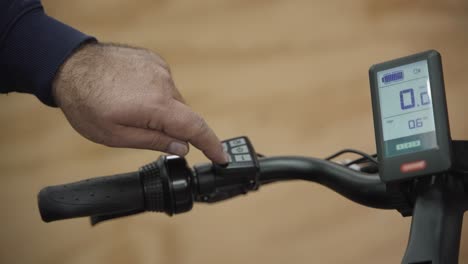 primer plano de un hombre ajustando la fuerza de aceleración de una bicicleta eléctrica dentro de su tienda