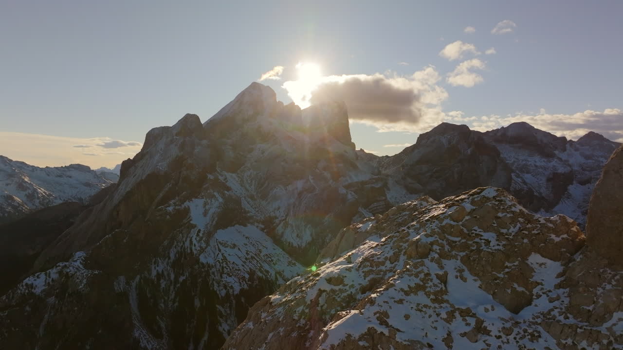 imágenes aéreas volando por las crestas de un pico de montaña con montañas y el amanecer corriendo en el fondo en italia.