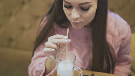 Langhaarige-Brünette-In-Rosa-Pullover-Schmeckt-Milchkaffee