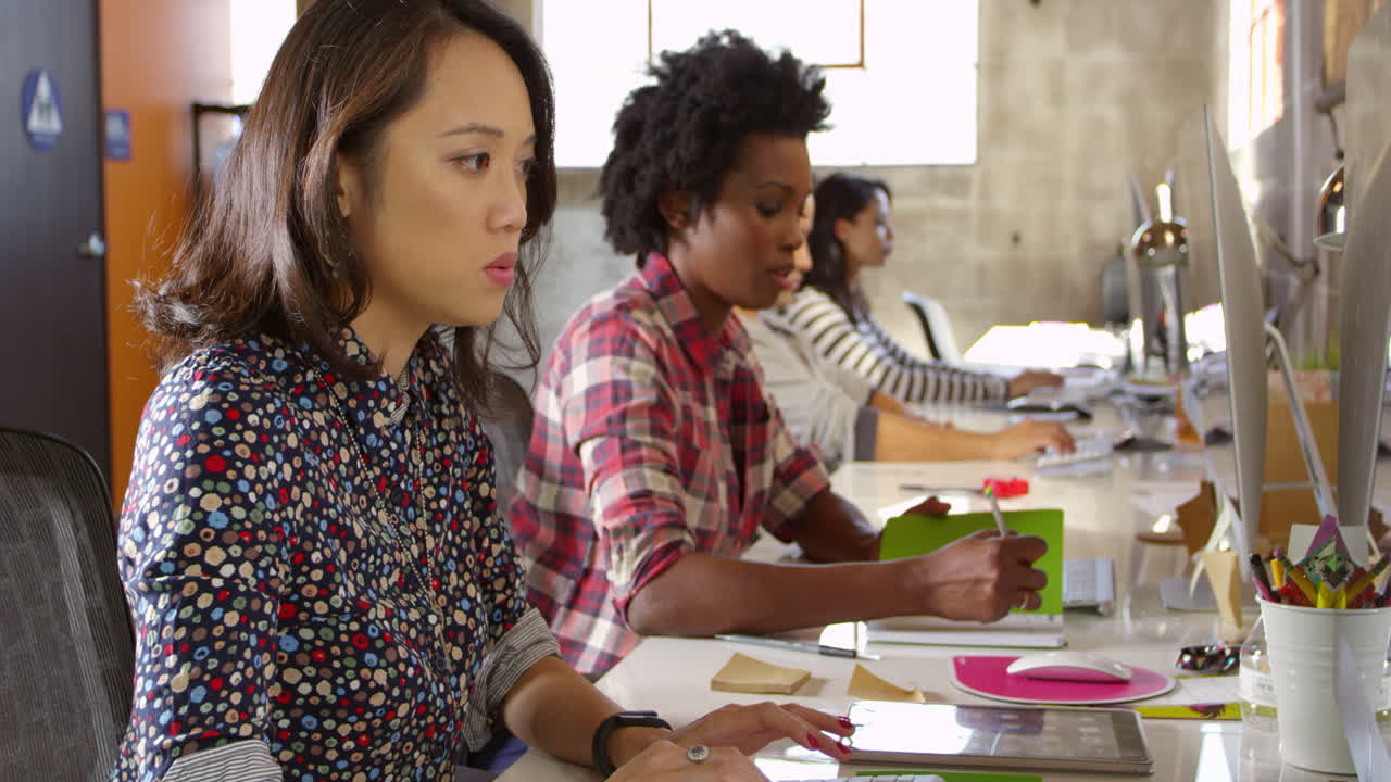 diseñadores trabajando en computadoras en oficinas modernas filmadas en r3d
