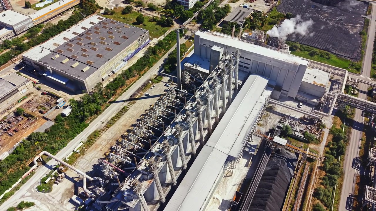 Large industrial factory with silos and buildings located in a manufacturing area during daylight hours
