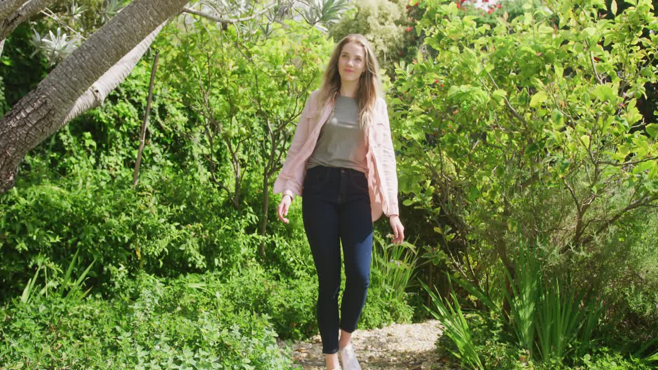feliz mujer caucásica caminando en el jardín en un día soleado