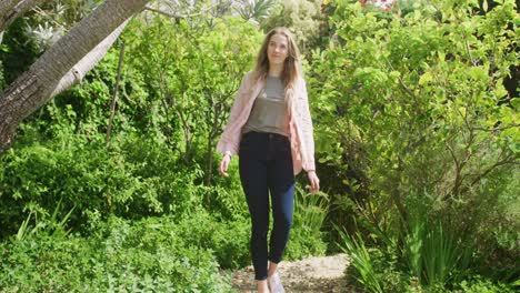 happy caucasian woman walking in garden on sunny day