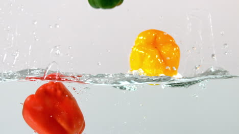 Peppers-falling-in-water-on-white-background