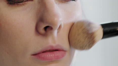 close up of applying setting powder on face of woman