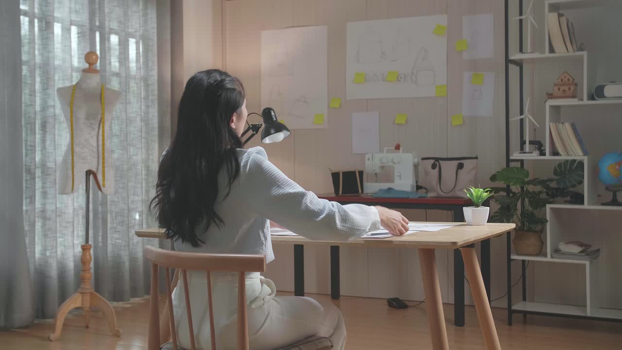 여성 디자이너의 뒷면은 사무실에서 레이아웃 본드를 그리는 동안 시도됩니다.