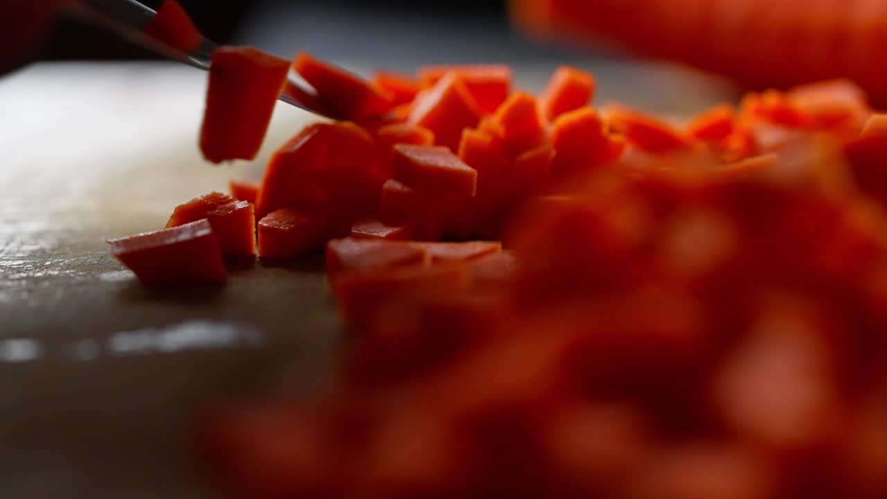 Close-up view of freshly chopped carrots on a cutting board, showing vibrant orange cubes prepared for cooking