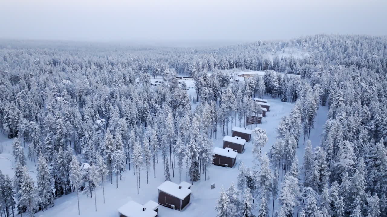 Aerial View of Snowy Forest Cabins in Winter Wonderland