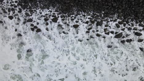 Static-top-down-drone-view-of-a-rugged,-rocky-beach-on-Hawaii's-Big-Island,-featuring-powerful,-frothy-white-waves