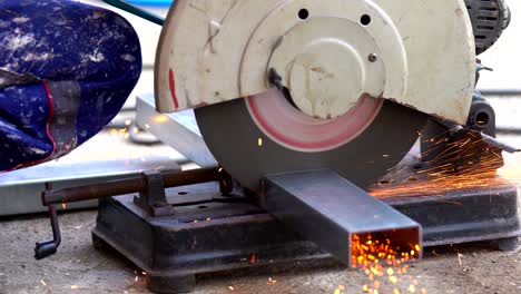 4k close up shot of construction worker welder hands using electric angular grinding machine for cutting iron steel bar and making sparks fire flakes from welding. safety work concept.