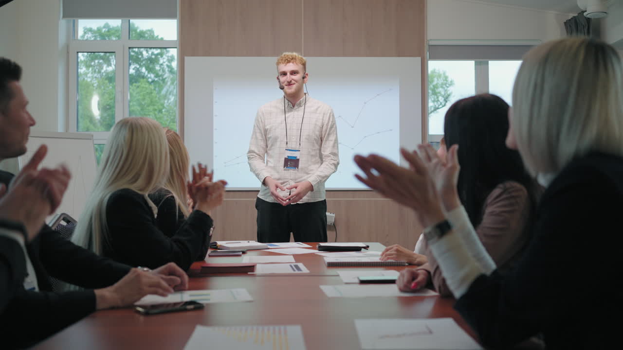 남성과 여성은 교육 세미나 또는 비즈니스 회의의 젊은 연설자에게 박수를 치고 환호하고 있습니다.