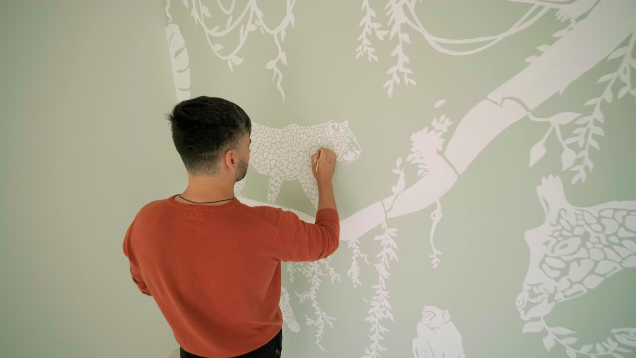 예술가는 어린이 방에서 그림으로 벽을 장식하고 있습니다. 새로운 집에서 벽의 예술 그림. 수리 작업.