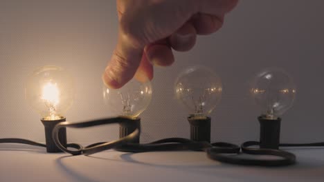 cuatro bombillas de filamento encendidas con una mano.
