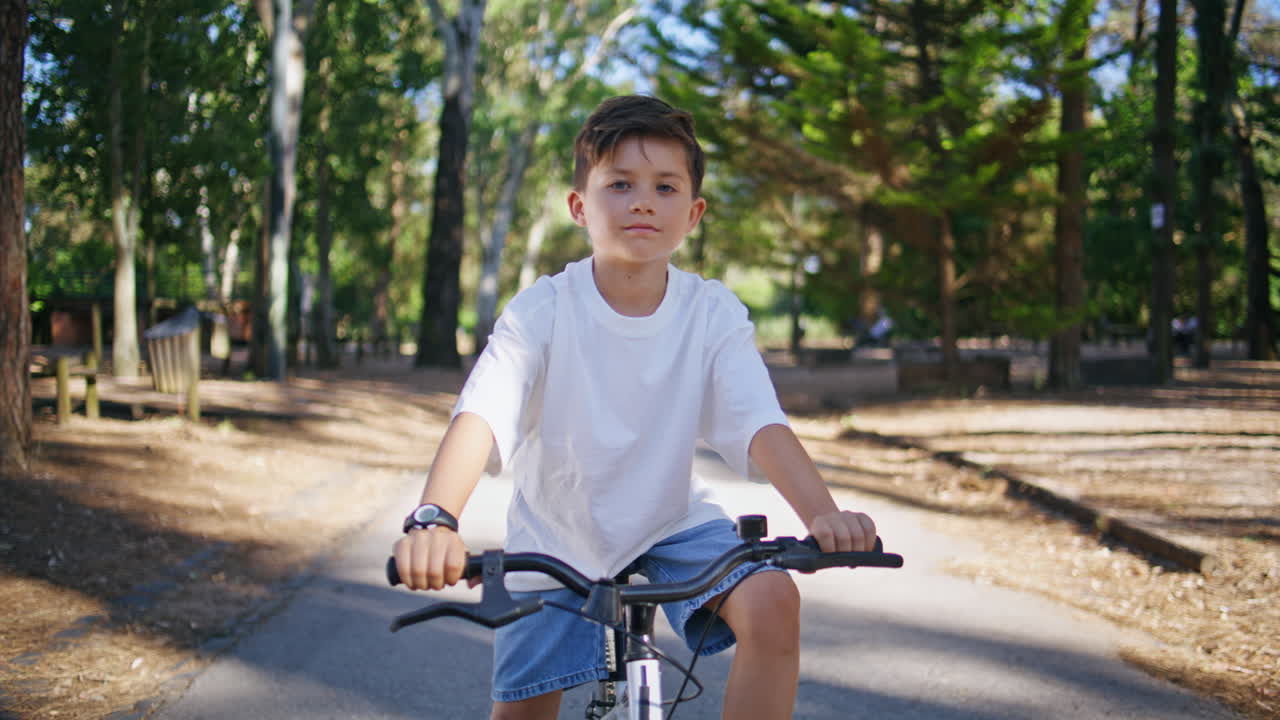 Small boy sitting bike at summer forest portrait. Little kid looking camera