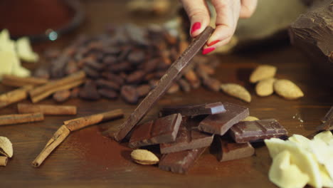 Mano-Femenina-De-Primer-Plano-Poniendo-Barra-De-Chocolate-Sobre-Una-Mesa-De-Madera.