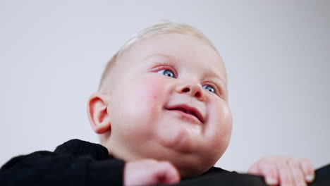 adorable chubby face of a caucasian infant boy. low angle view on the smiling blond baby. close up.